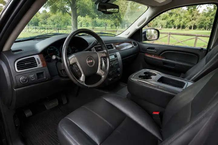 GMC SUV dashboard with leather steering wheel, wood trim accents, and black leather front seats