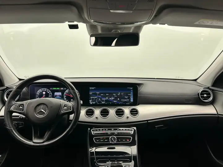 Mercedes-Benz E-Class dashboard with leather steering wheel, digital instrument cluster, and widescreen navigation display