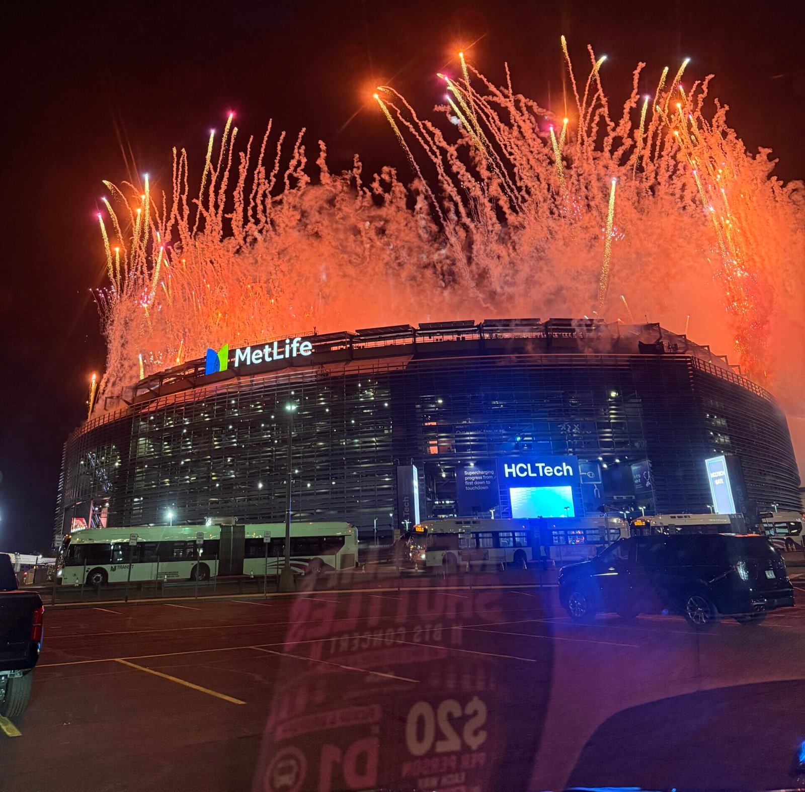 Fireworks display over MetLife Stadium at night with limousine service vehicle in foreground