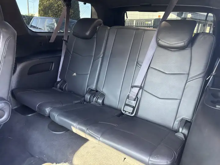 Black leather third-row bench seat in a Cadillac Escalade with visible crest on the headrest