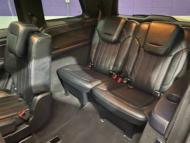 Black leather third-row captain's chairs in a luxury SUV, viewed from the second row