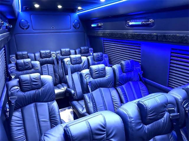 Rows of black leather captain's chairs inside an executive Sprinter van with blue ambient lighting