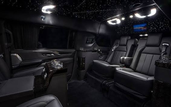 Luxury SUV interior with black leather captain's chairs, a starlight ceiling, and a rear screen