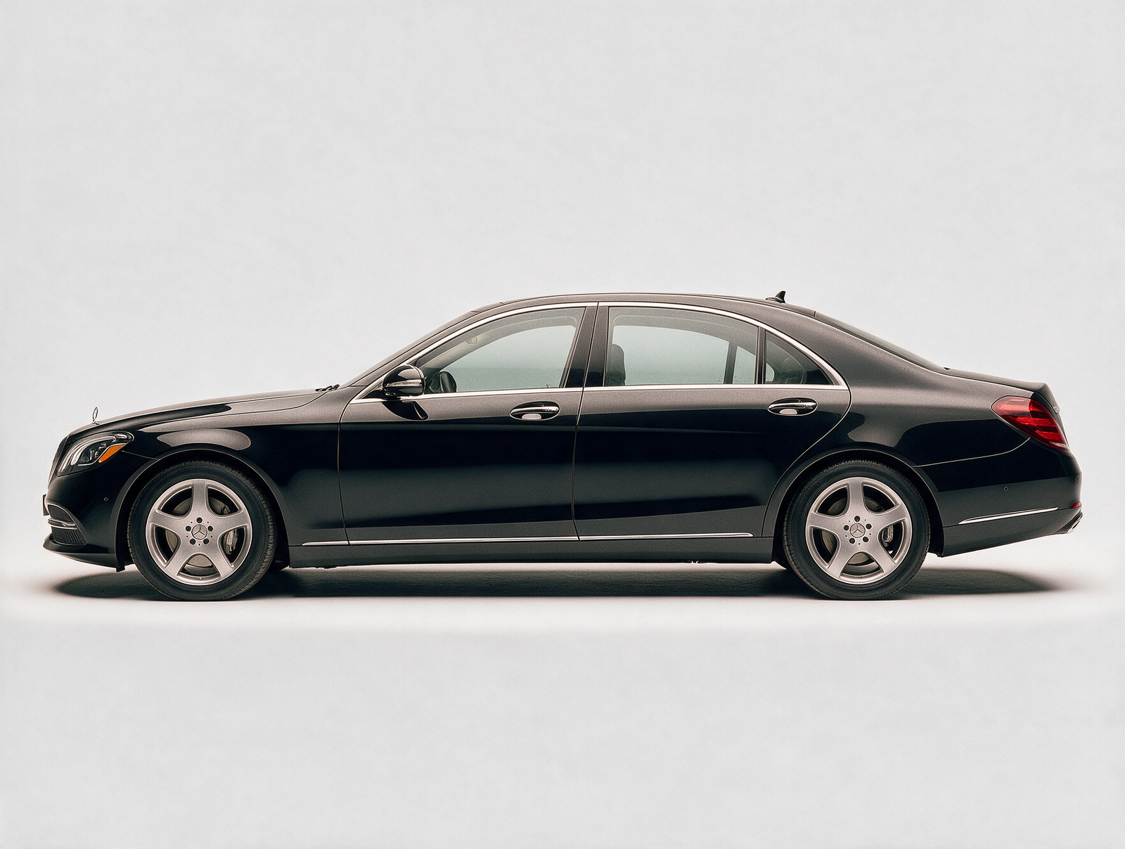 Black Mercedes-Benz S-Class luxury sedan side profile on white studio background